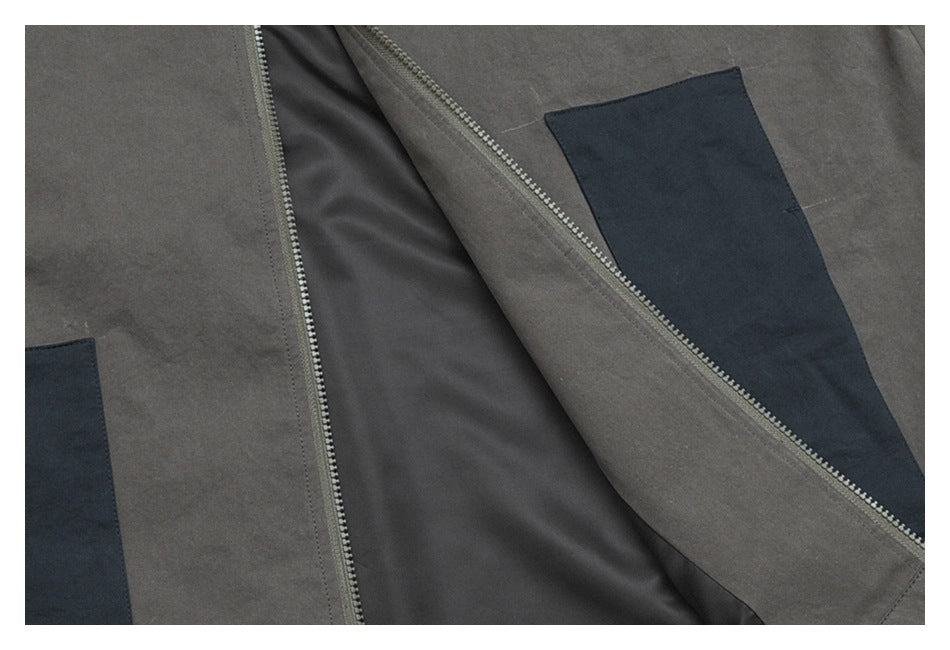 Close-up of the open charcoal jacket, showing its dark lining, front zipper, and contrast pocket panels.