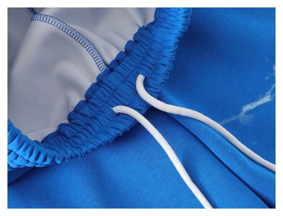 Close-up of bright blue pants showing the elastic waistband, white drawstring, and interior stitching.