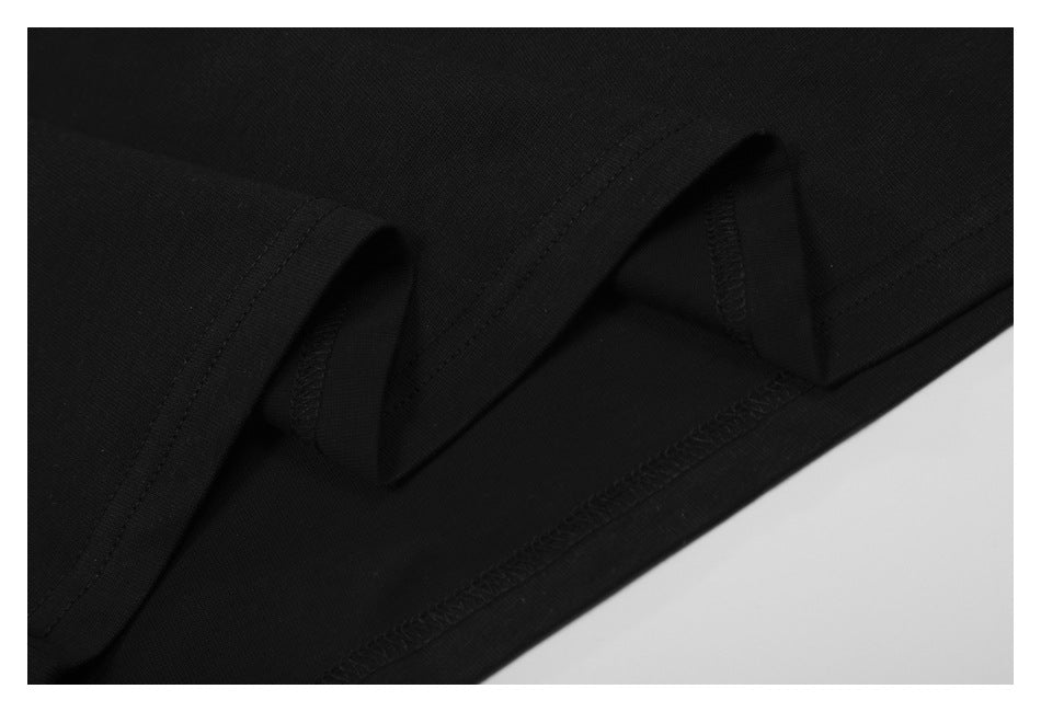 Close-up of black garment seam finishing, showing folded fabric and overlock stitching along the hem.