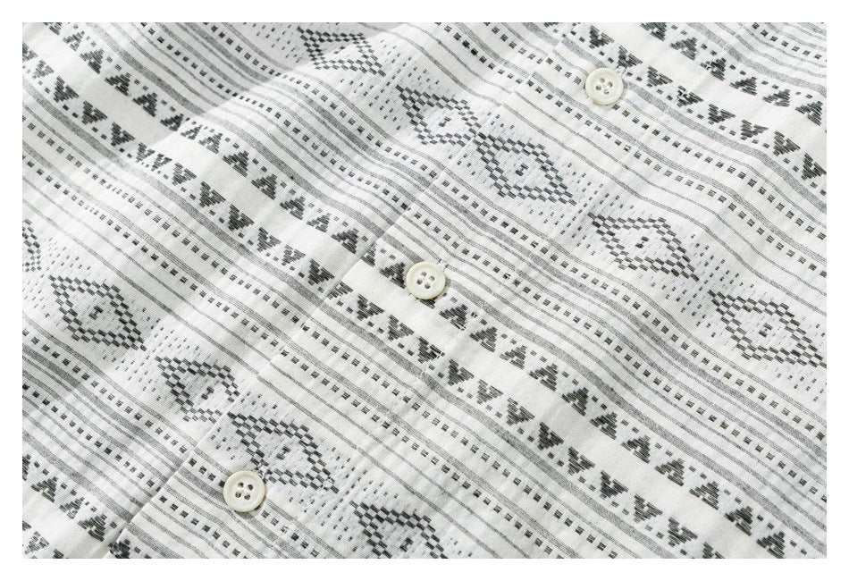 Close-up of the white shirt's black geometric stripe pattern and three light-colored buttons.