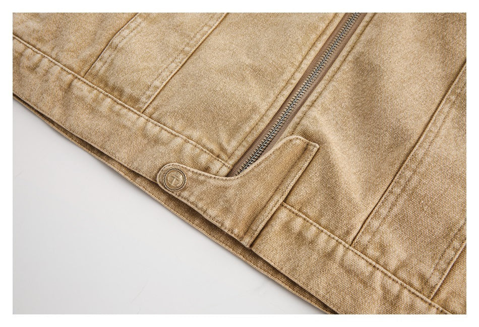 Close-up of a tan jacket hem with a metal zipper and a buttoned tab.