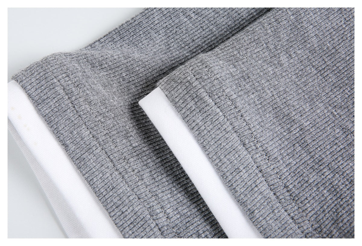 Close-up of a heather-gray ribbed garment edge with visible stitching and a white layer beneath.