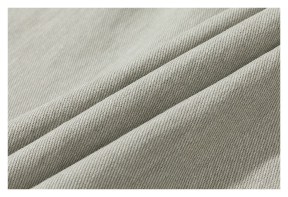 Macro view of the pale gray-beige fabric's diagonal woven texture and folded edge.
