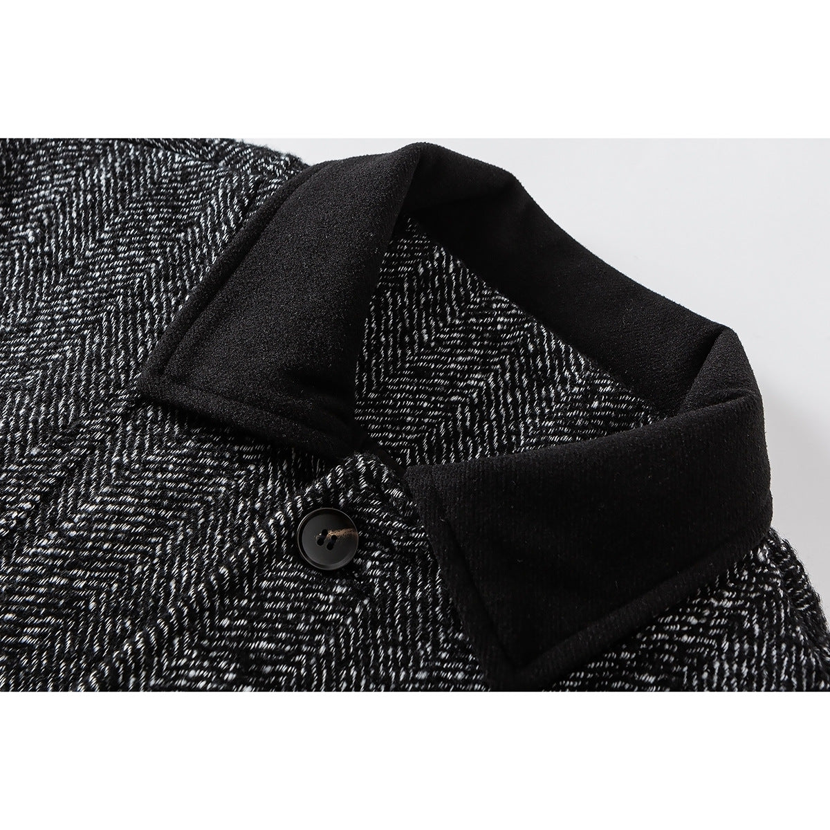 Close-up of a black-and-white herringbone jacket with a wide black collar and a dark button.