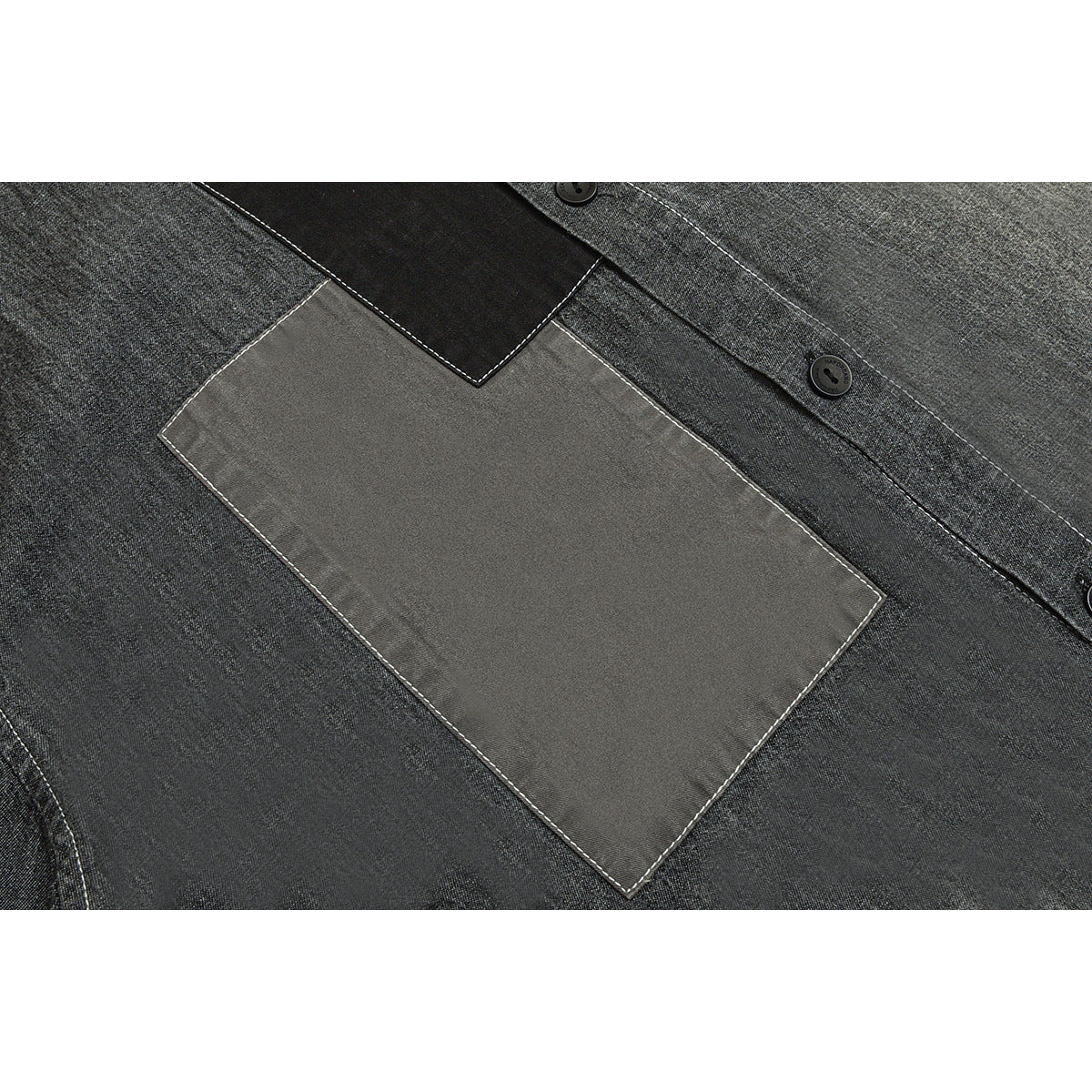 Close-up of a large rectangular gray chest patch pocket on a charcoal shirt with white stitching and black buttons.