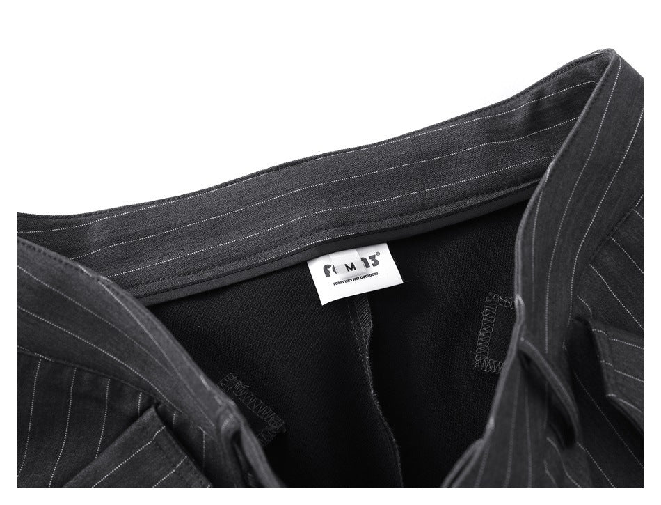 Close-up of the inside waistband of charcoal pinstripe trousers, showing a small white brand label and black lining.