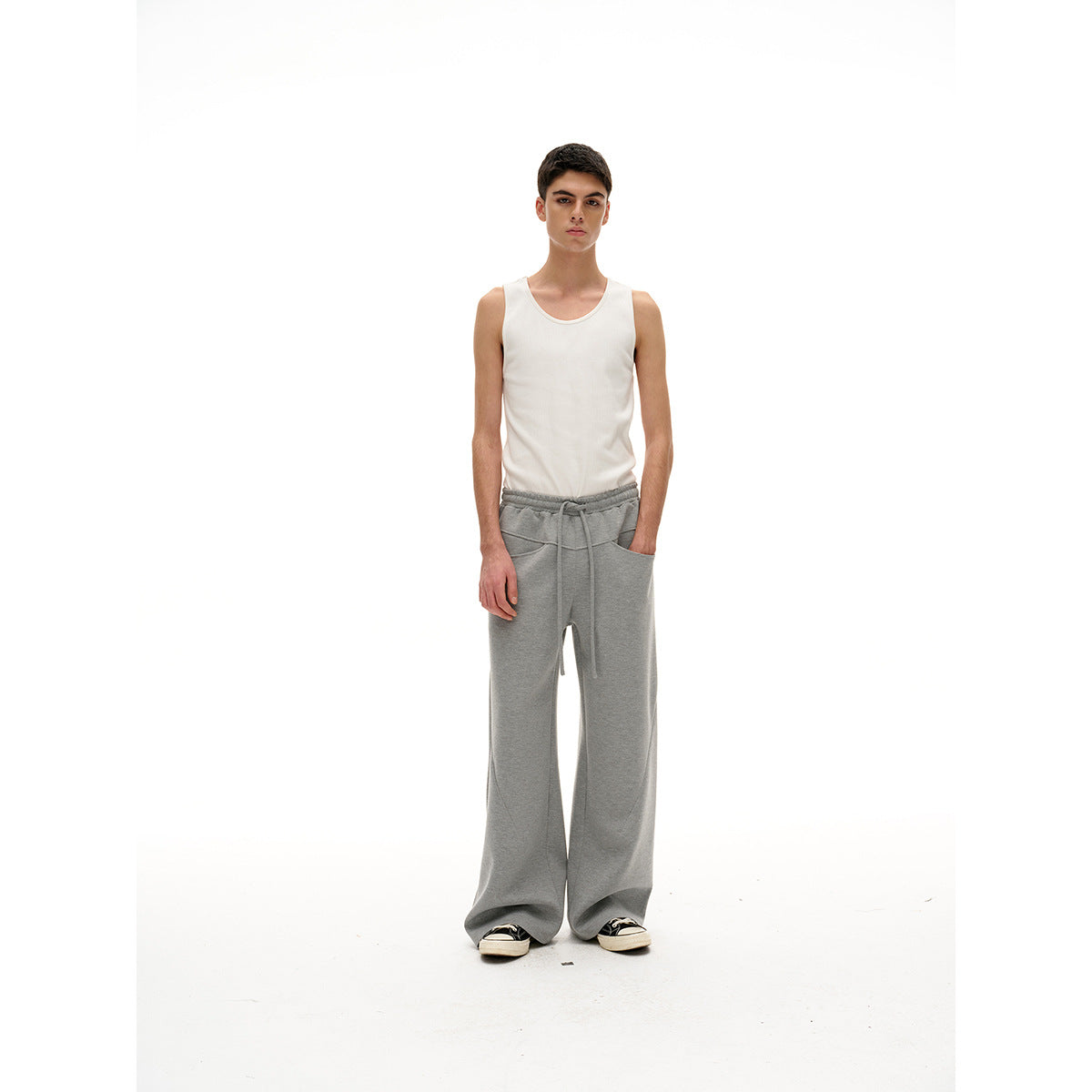 Model wearing a white tank top and gray wide-leg drawstring pants, shown full-length from the front.