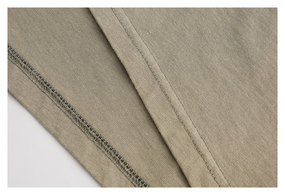 Close-up of tan fabric with an overlocked edge and a parallel line of stitching.