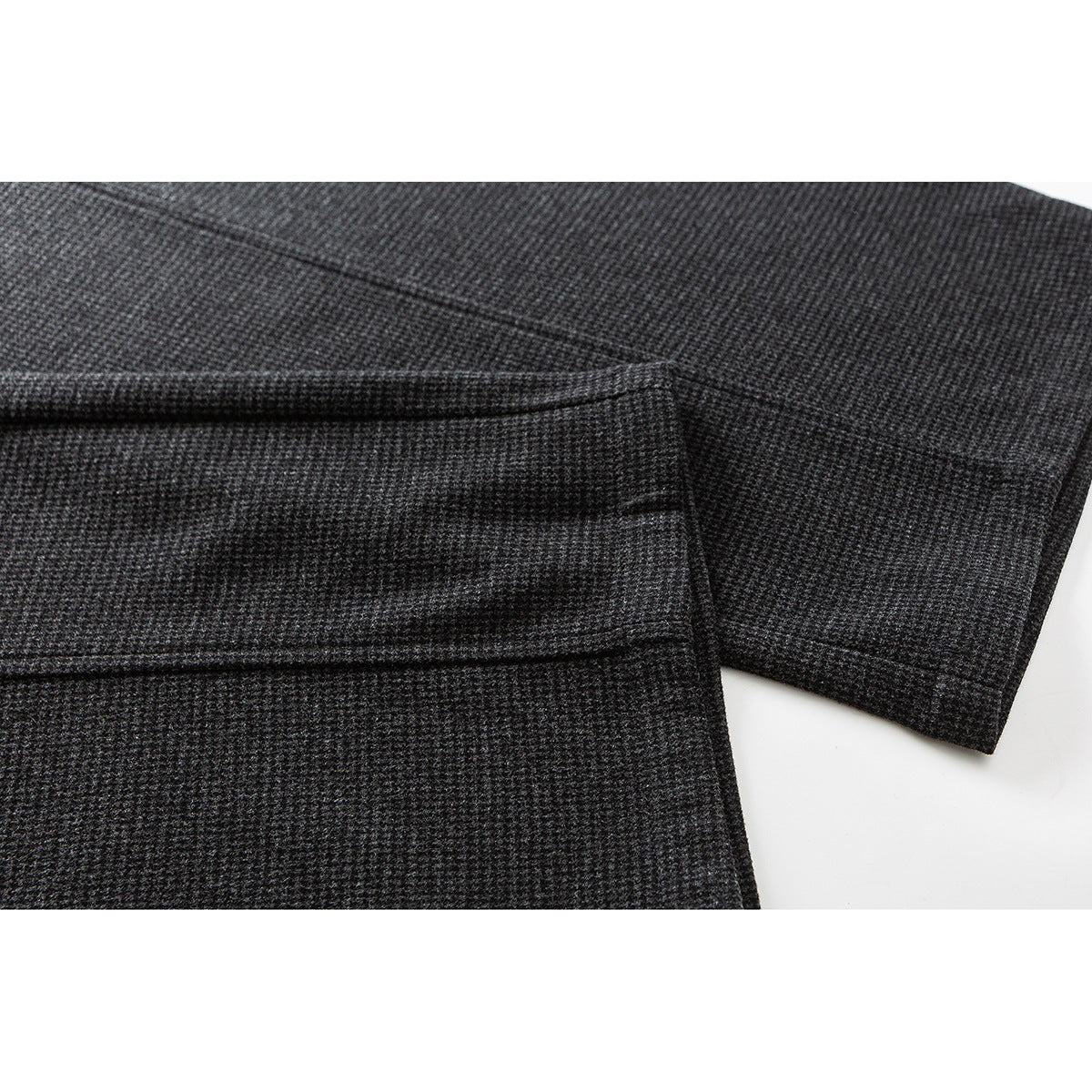 Close-up of the hem and folded leg of charcoal gray patterned trousers.