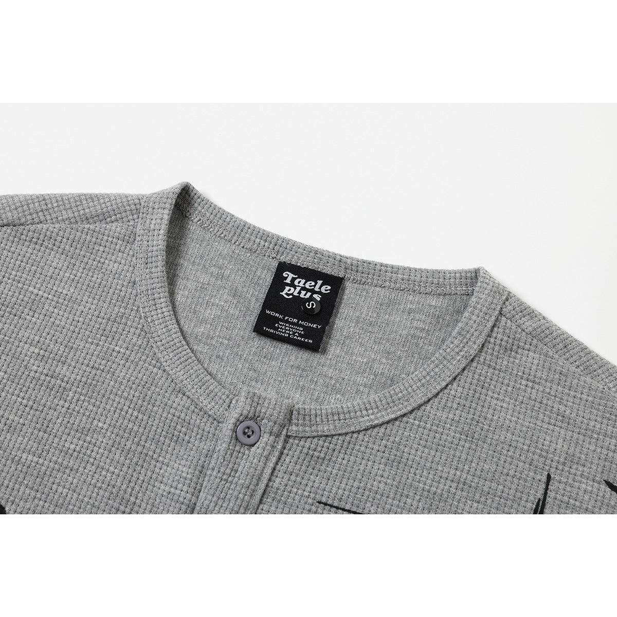 Close-up of a gray waffle-knit shirt neckline with a button placket and black woven neck label.