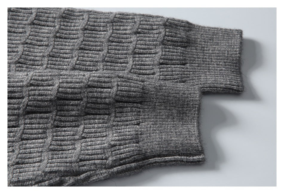 Close-up of a gray knit sweater sleeve and ribbed cuff with a raised geometric pattern.
