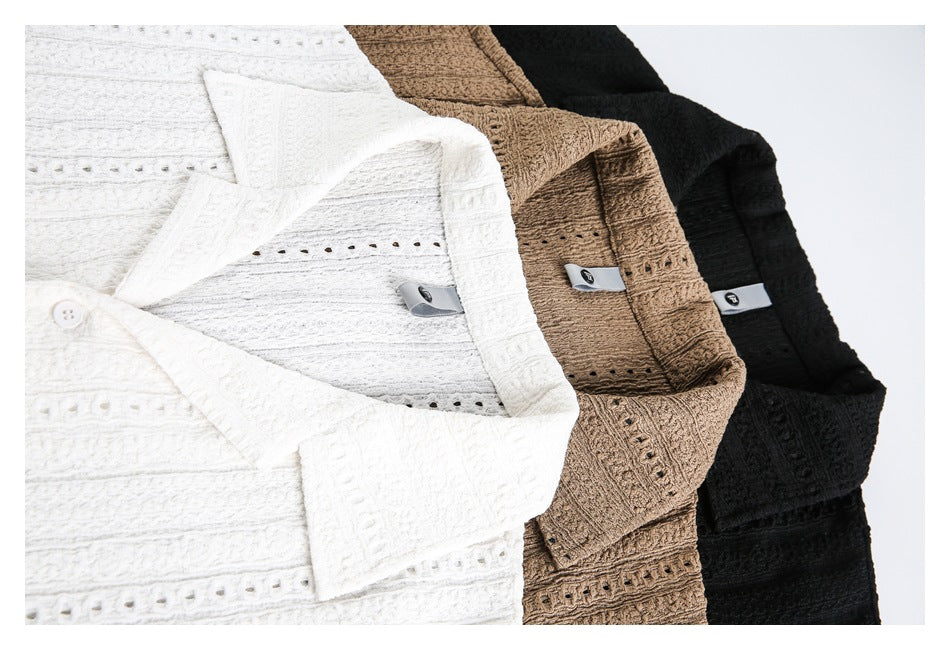 Close-up of white, tan-brown, and black shirts showing their collars, buttons, textured fabric, and openwork stripes.