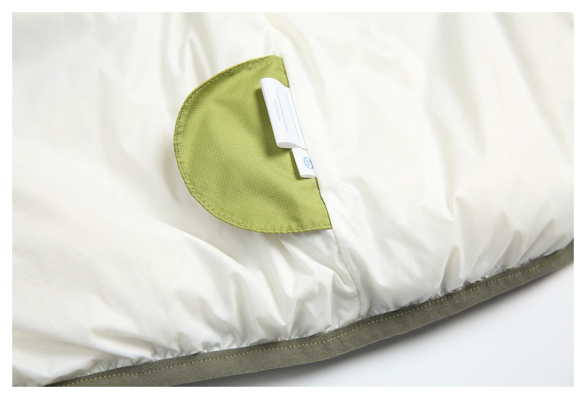 Close-up of white garment fabric with an olive-green mesh pocket and olive-gray bound edge.