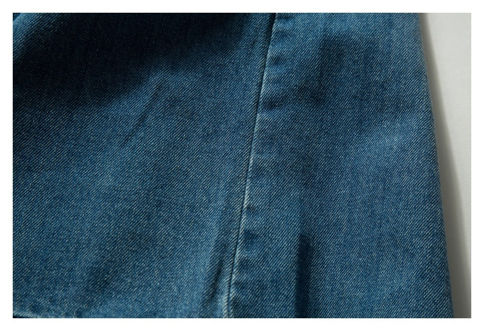 Close-up of blue denim fabric with a vertical seam and subtle fading.