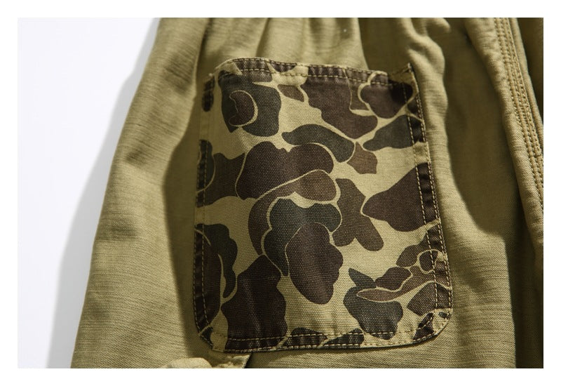 Close-up of a brown camouflage-patterned pocket sewn onto khaki shorts.