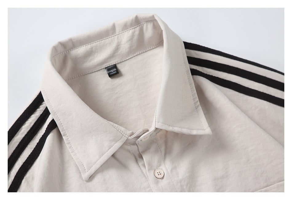 Close-up of the off-white shirt's pointed collar, top button, neck label and black shoulder stripes.