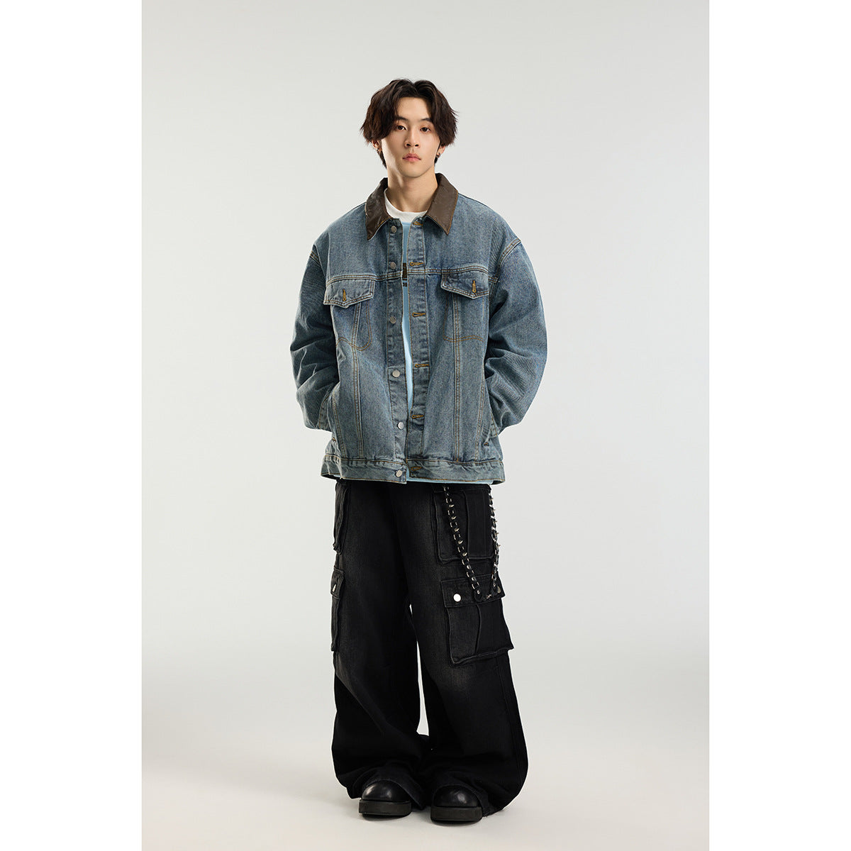 Full-length view of a model wearing an oversized blue denim jacket with a brown collar and black cargo pants.
