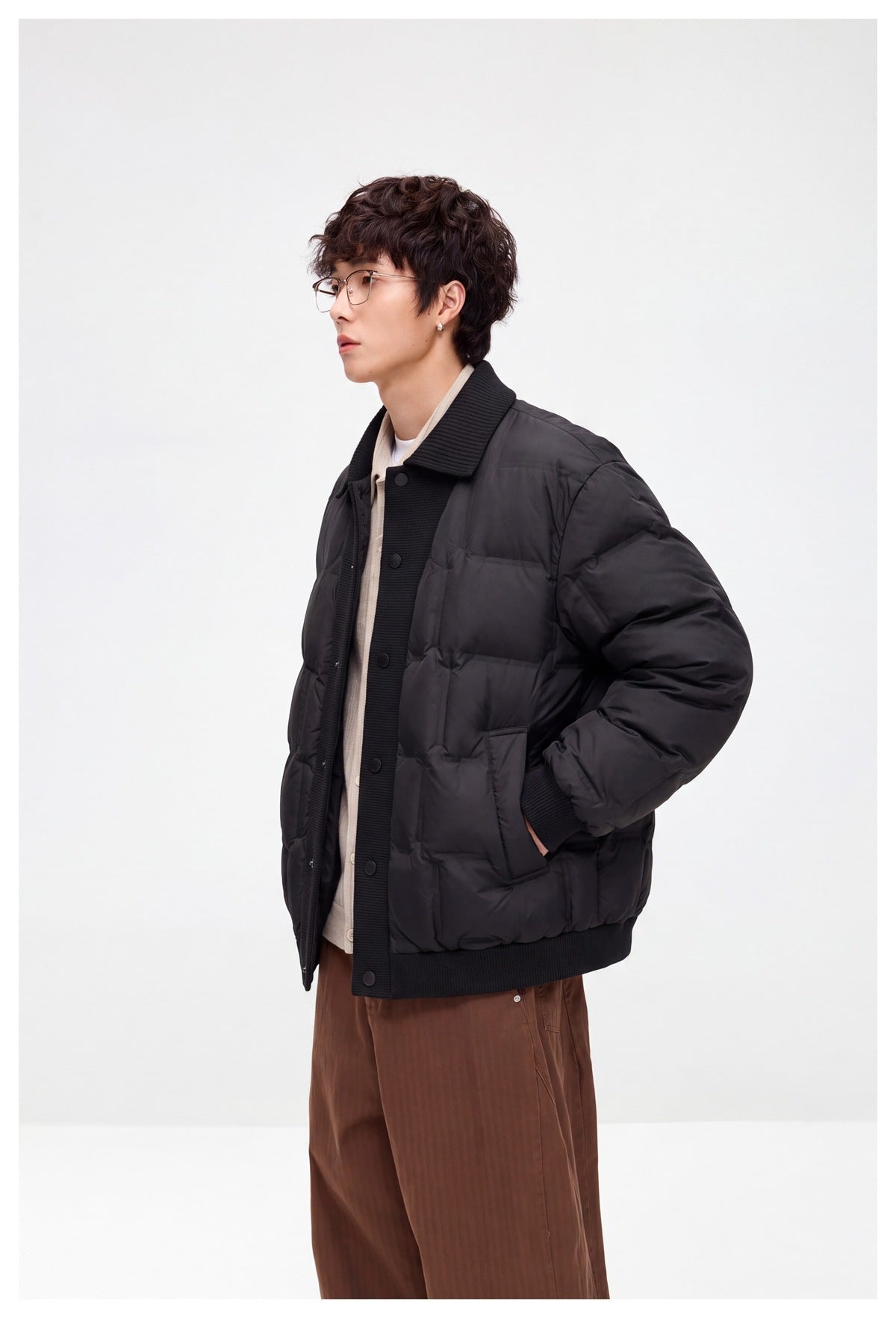 Model wearing a dark quilted jacket, shown from the side with its ribbed collar and hem and front buttons visible.