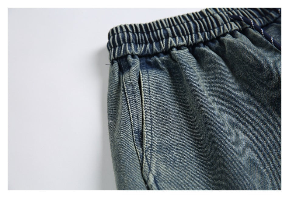 Close-up of blue denim pants with an elastic waistband and side pocket seam.