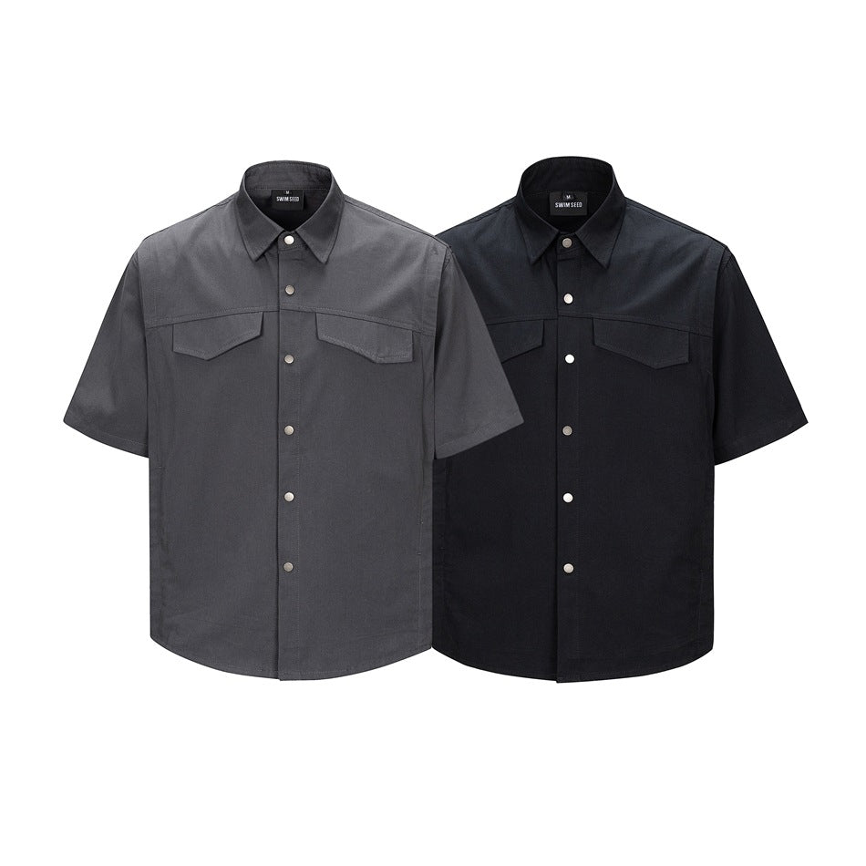 Two short-sleeve snap-front shirts shown from the front, one charcoal gray and one black, each with two flap chest pockets.