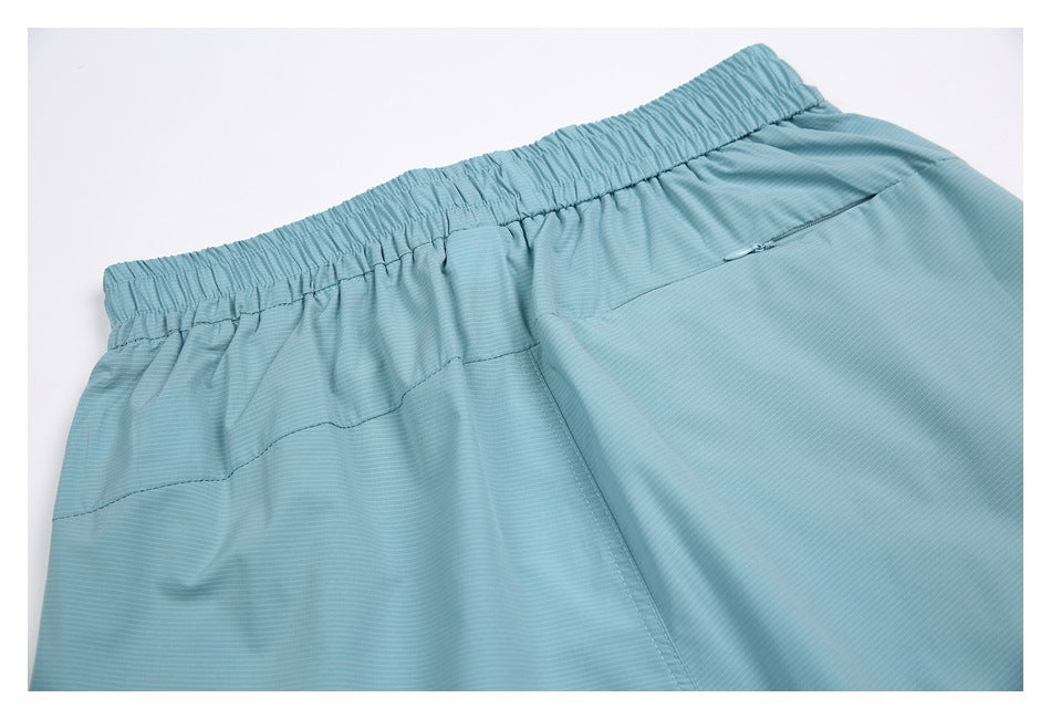 Close-up of the elastic waistband and zip pocket on aqua shorts.