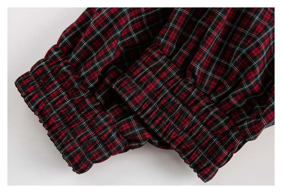 Close-up of gathered elastic edging on red, black, and white plaid fabric.