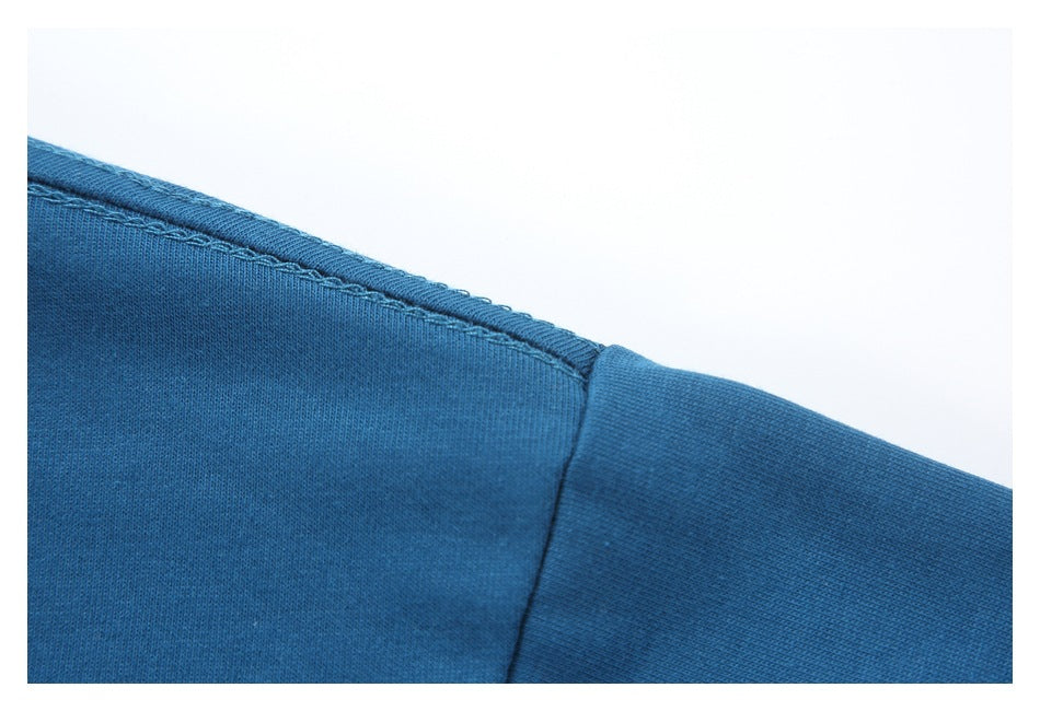 Close-up of blue garment fabric and stitched seam beside a sleeve or panel.