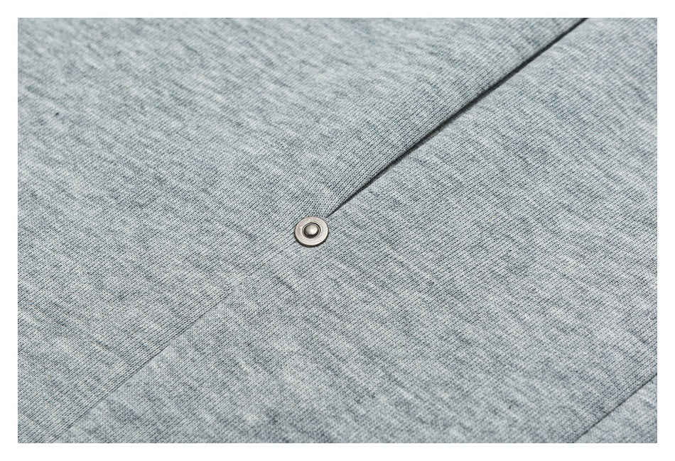 Close-up of a round metal snap set into heather gray pants fabric.