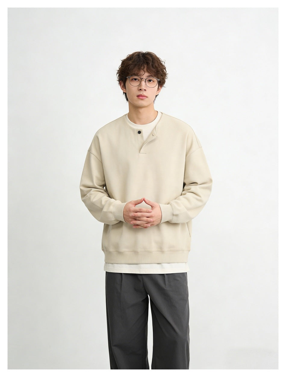 Front view of a model wearing a cream oversized sweatshirt with a single-button placket.
