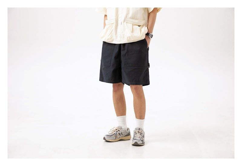 Front view of a model wearing black knee-length shorts with large front patch pockets.