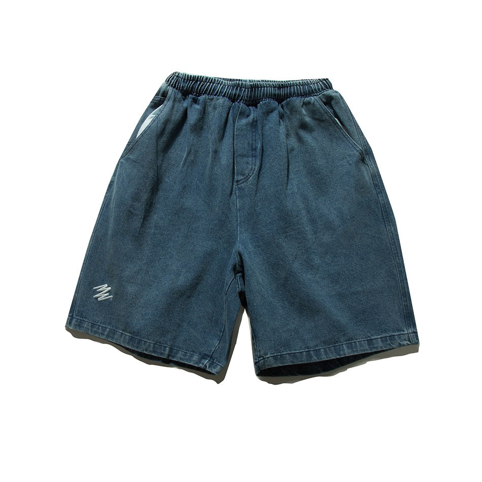 Dark blue washed denim shorts front view with elastic waistband, side pockets and small embroidered mark on the leg