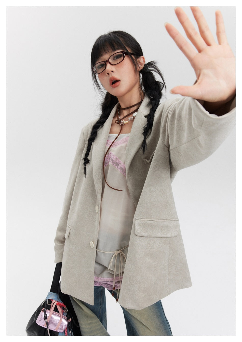 Model in a light beige patterned blazer with notched lapels, pale buttons and flap pockets.