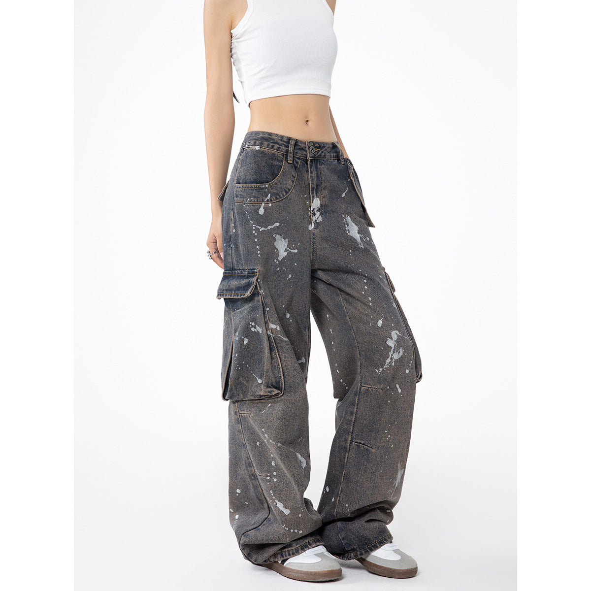 Model wearing charcoal-gray, paint-splatter cargo jeans with oversized side pockets and wide legs, shown at an angle.