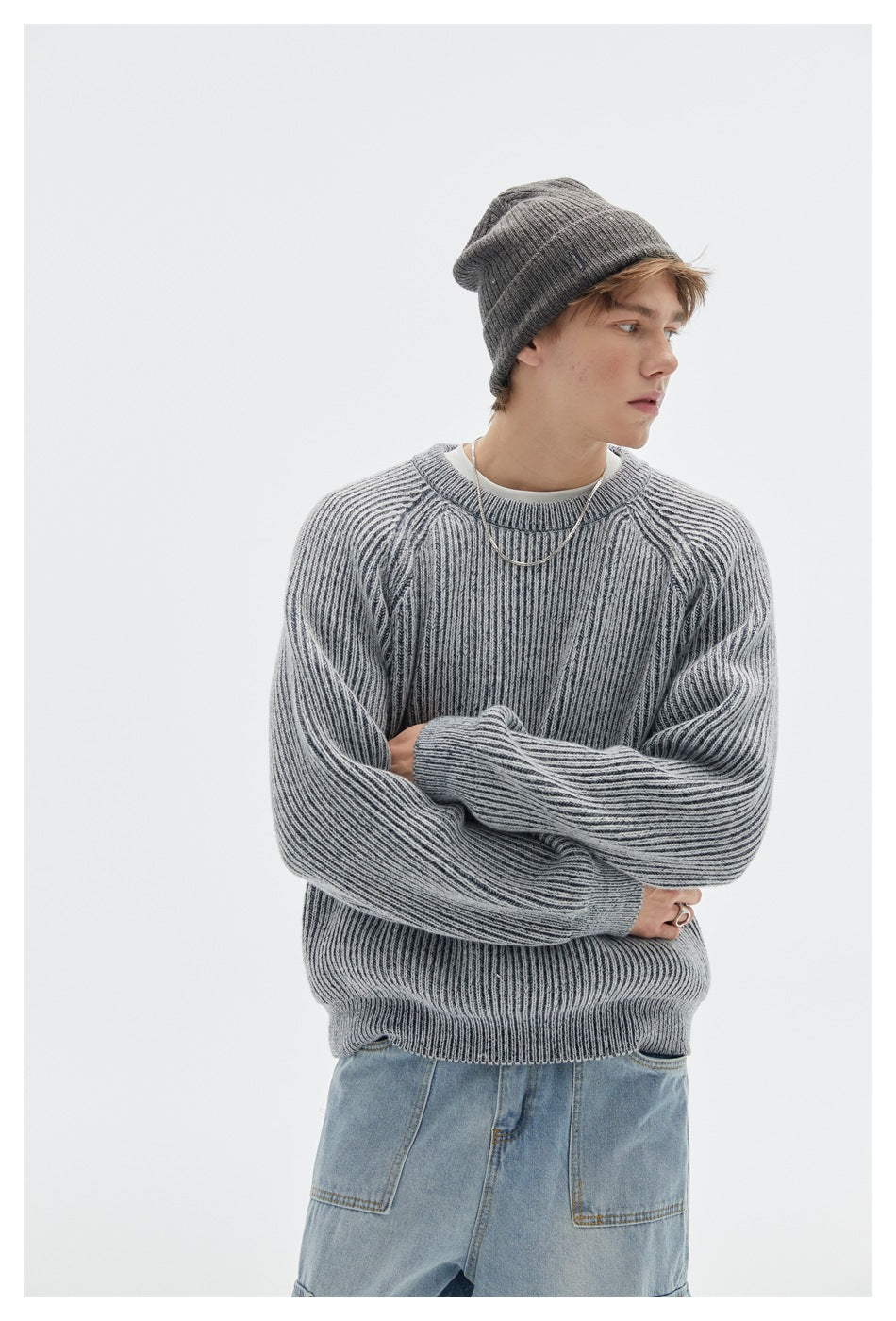 Model wearing a light gray ribbed crewneck sweater with raglan sleeves, a charcoal beanie, and jeans.