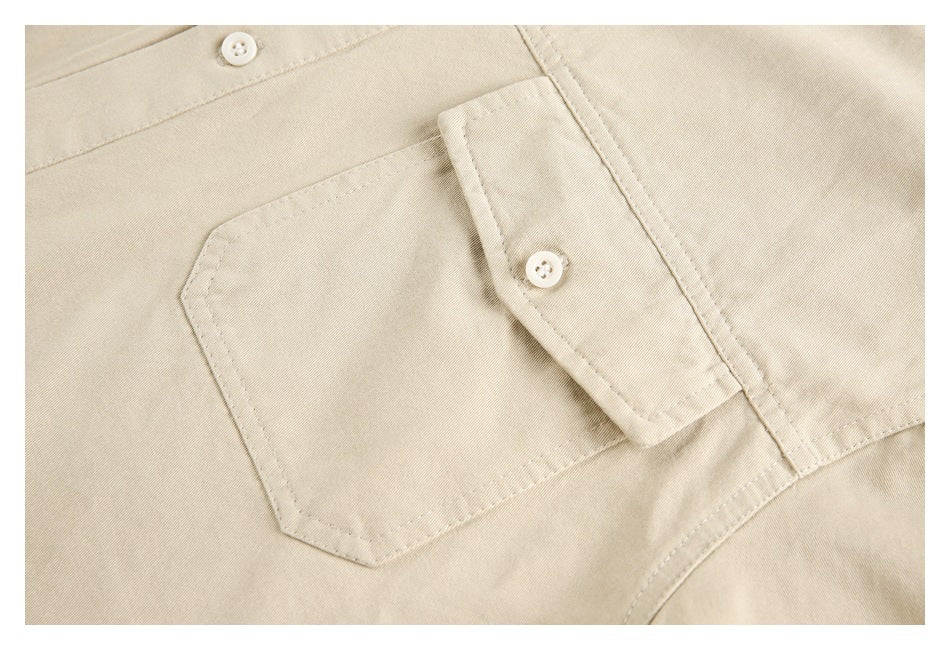 Close-up of a beige shirt chest pocket with a buttoned flap and visible stitching.