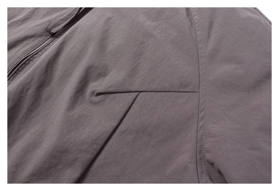Close-up of a horizontal welt pocket and stitched seams on a dark gray jacket.