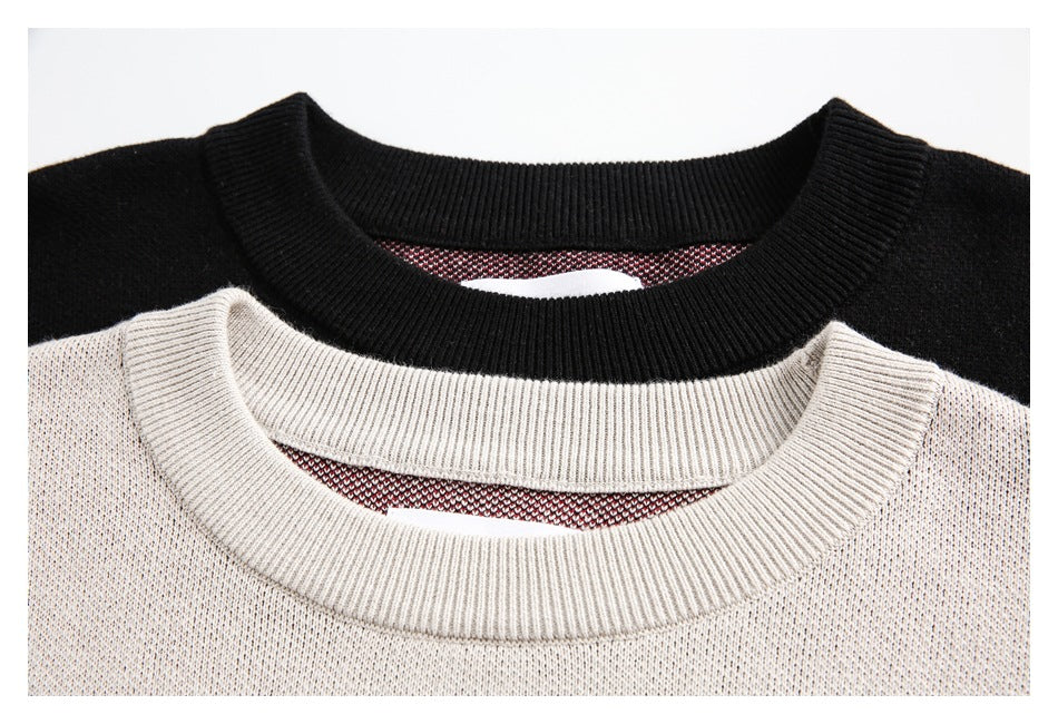 Close-up of black and light gray sweater necklines, showing ribbed crew collars and knit texture.