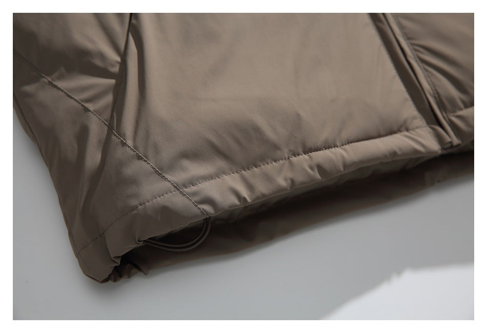 Close-up of a stitched hem on taupe garment fabric, with a dark loop visible underneath.