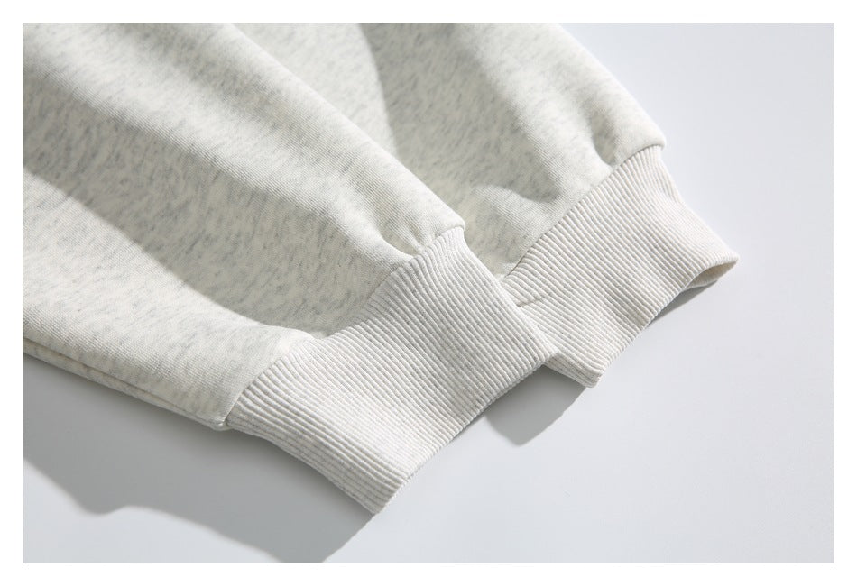 Close-up of two wide ribbed cuffs on the sleeves of a heathered light-gray sweatshirt.