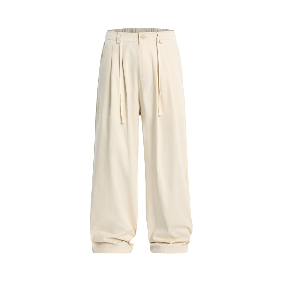 Apricot cream wide-leg pleated trousers with button front and drawcord ties, flat front view