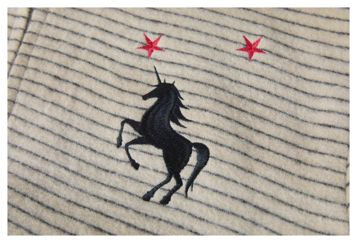Close-up of cream fabric with thin dark stripes and embroidered black rearing horse with two red stars.