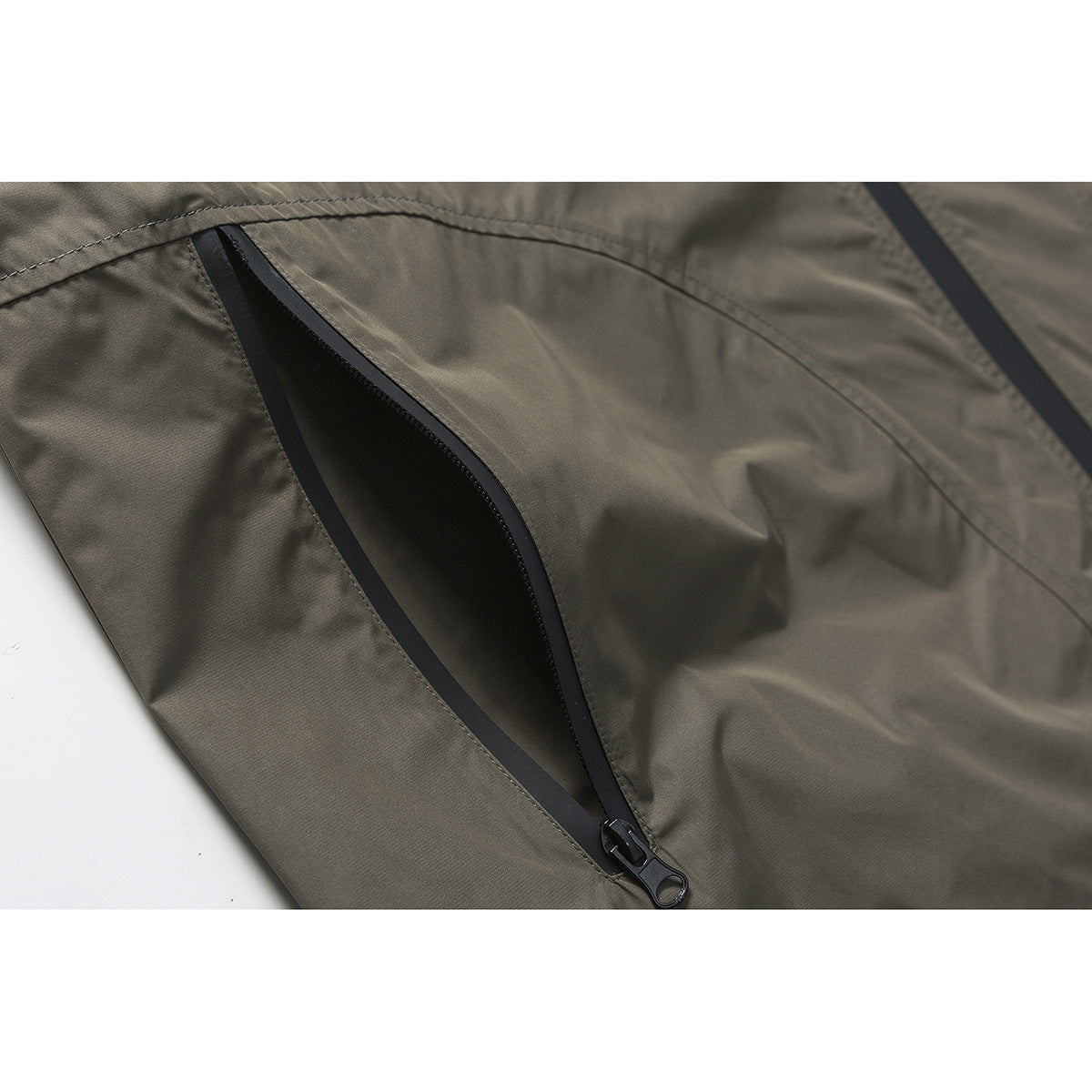 Close-up of an open black zipper pocket on an olive-gray jacket.