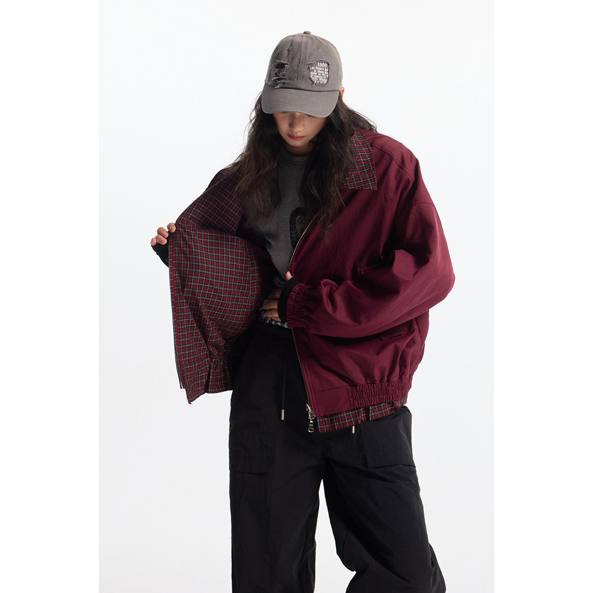 Model opens a burgundy jacket to show its red-and-green plaid lining and collar.