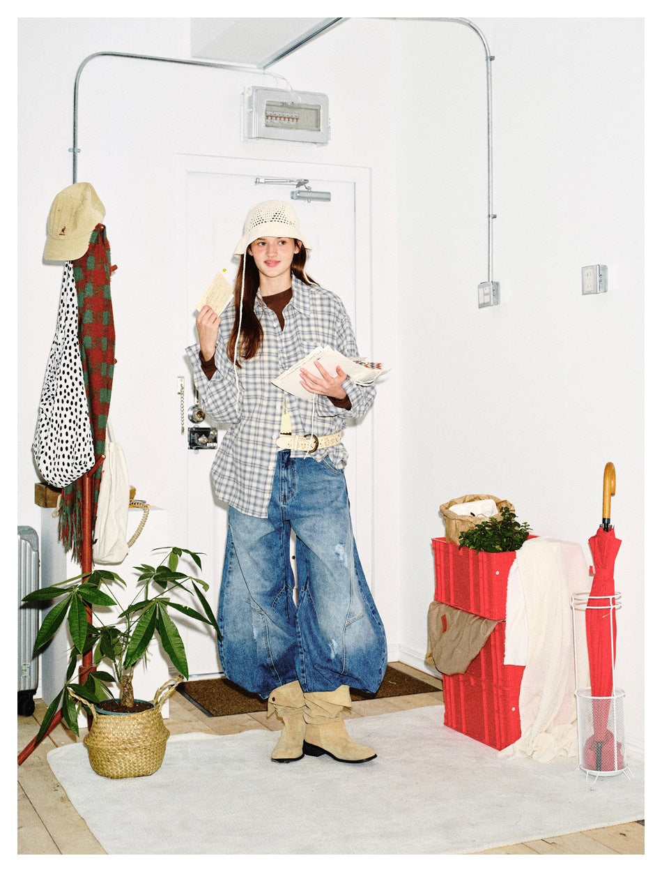 Model wearing a blue-gray plaid button-up shirt with oversized jeans and a cream crochet hat.