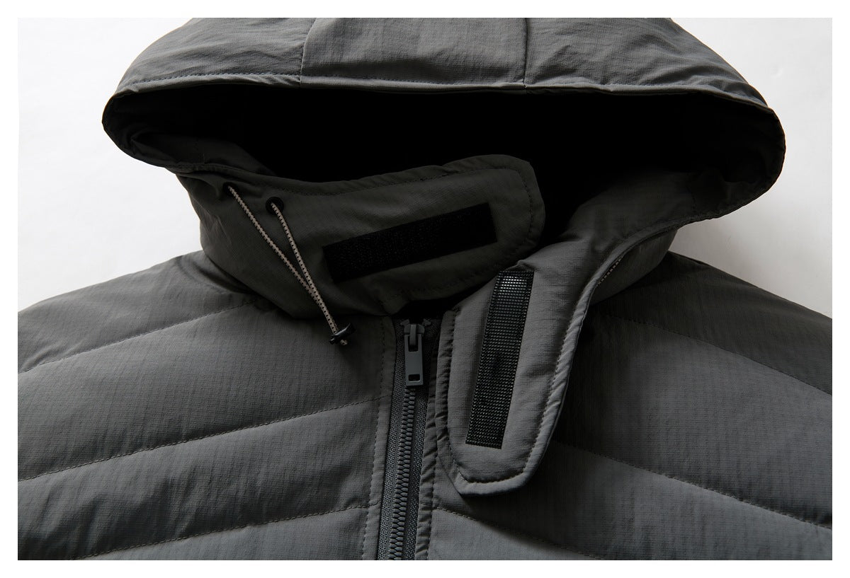 Close-up of a charcoal gray quilted jacket hood, drawcords, zipper and black hook-and-loop fastening tabs.