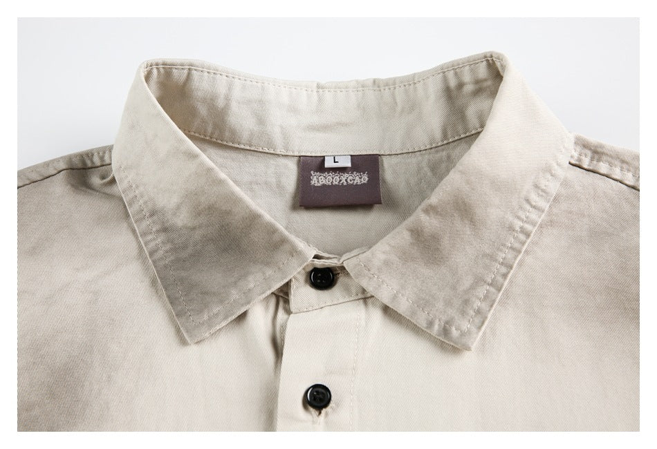 Close-up of a beige shirt collar, black buttons, and a sewn-in neck label.