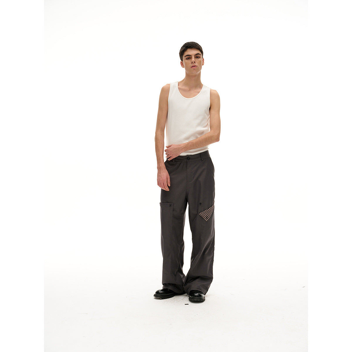 Model wearing a cream tank top and charcoal wide-leg trousers with plaid pocket accents, shown full length from the front.