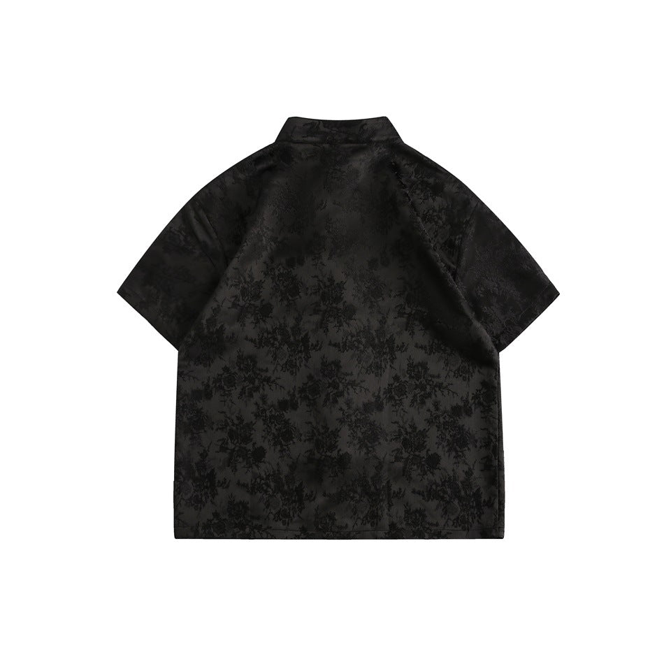Back view of a black short-sleeve top with a standing collar and tonal floral pattern.