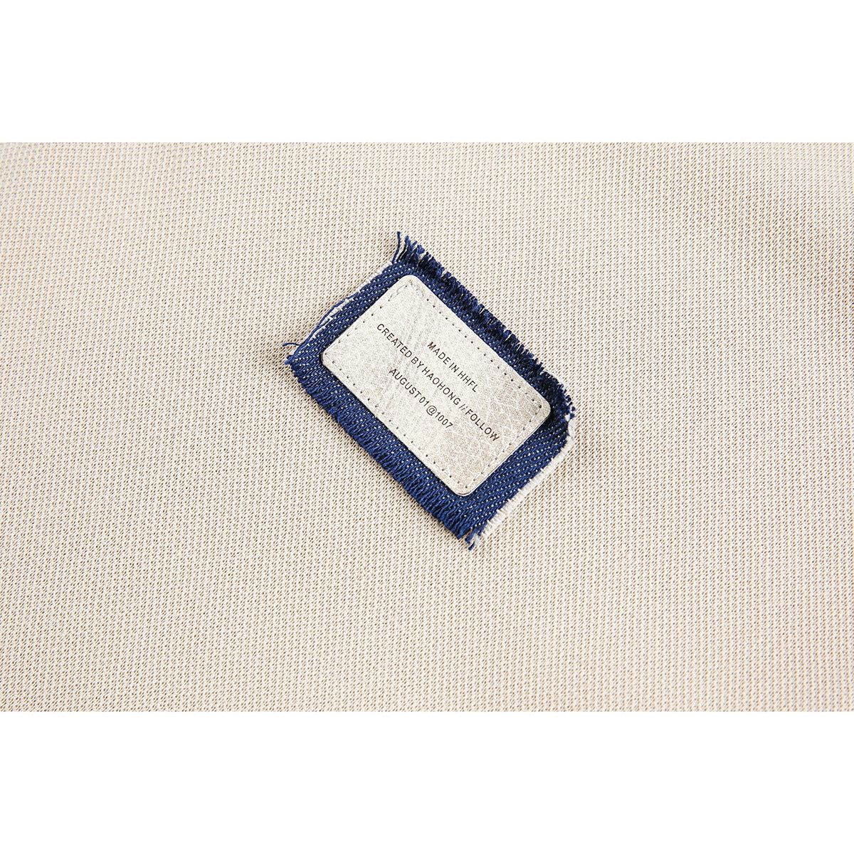 Close-up of a cream knit garment showing a small sewn label with a navy fabric border and English text.