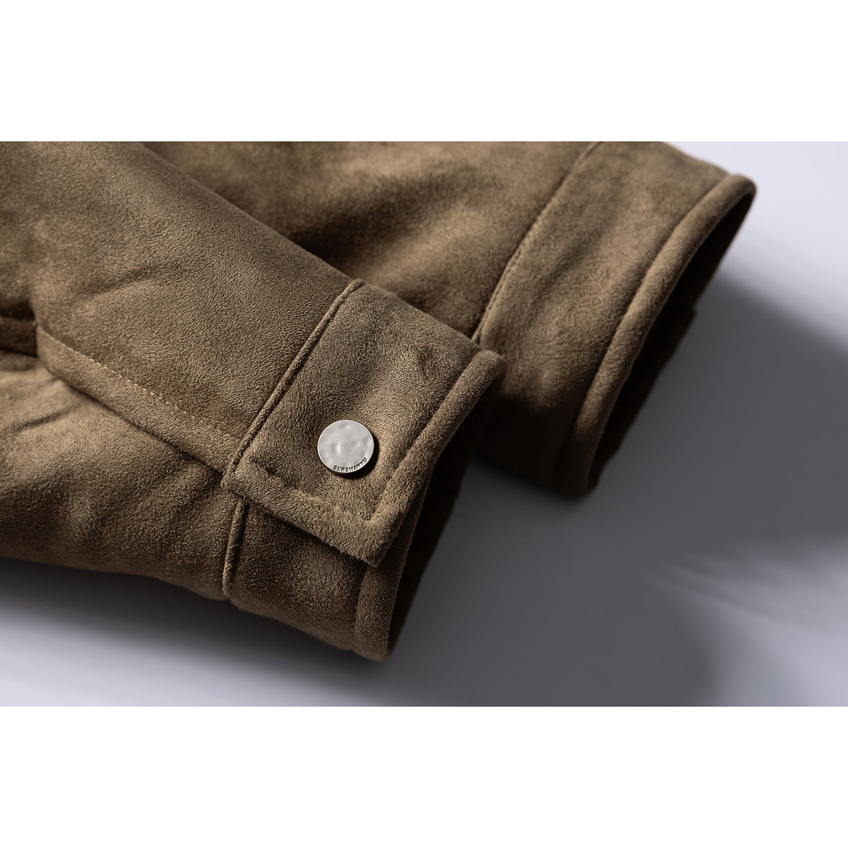 Close-up of the jacket's brown sleeve cuff, folded with a round silver snap button.